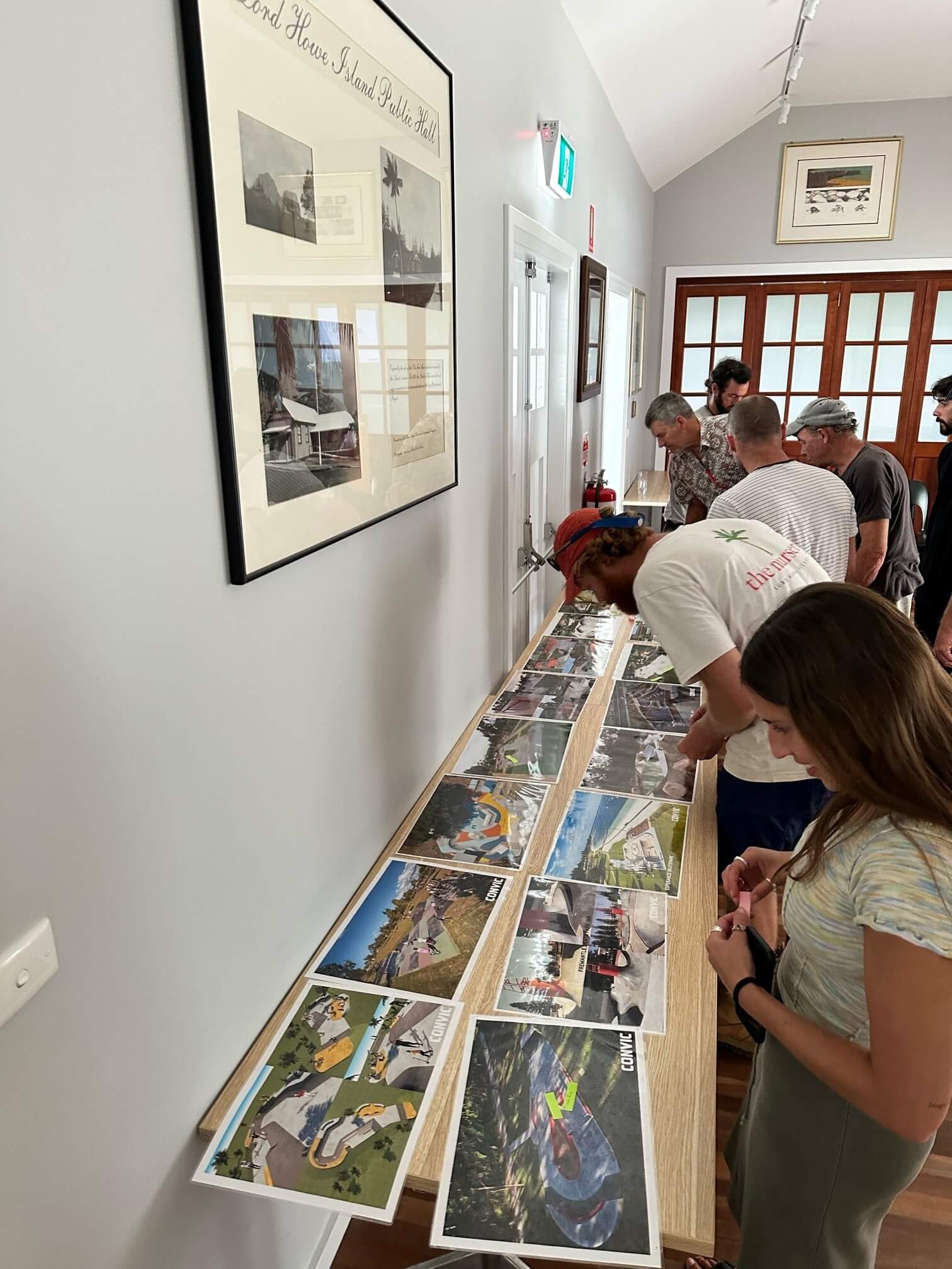People looking at different photos on a desk depicting design concepts for a skatepark